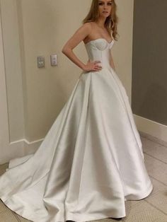 a woman in a white wedding dress standing next to a doorway with her hands on her hips