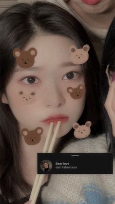 two girls with bear stickers on their faces holding chopsticks in front of them