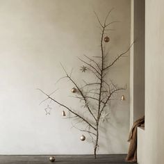 a christmas tree with ornaments hanging from it's branches in front of a white wall