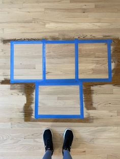 a person standing in front of a wooden floor with blue frames on it and their feet propped up