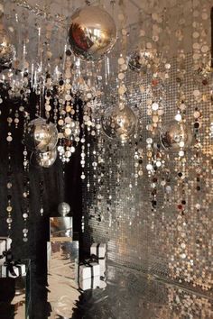 a room filled with lots of shiny balls hanging from it's ceiling next to a mirror