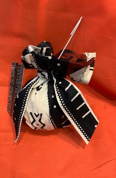 a black and white bow tie on an orange cloth with some scissors in it's pouch