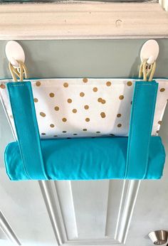 a blue and white purse hanging on a door handle in front of a mirror with gold polka dots