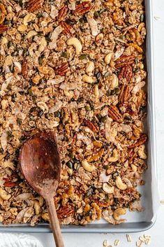 a pan filled with granola next to a wooden spoon