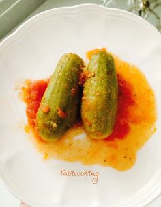 two pickles with sauce on a white plate