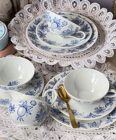 blue and white porcelain dishes with lace doily on tablecloth, next to decorative items