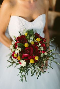 a bridal holding a bouquet of red and yellow flowers