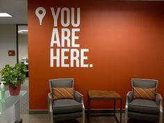 two chairs in front of a wall with the words you are here on it