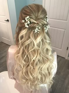 the back of a woman's head with long blonde hair and flowers in her hair