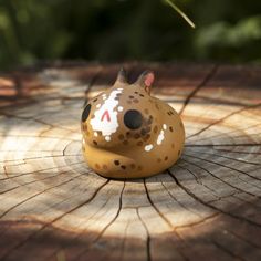 a small ceramic animal sitting on top of a tree stump in the sun or shade