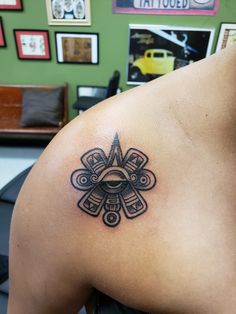 a man with a tattoo on his shoulder has an all seeing eye in the center