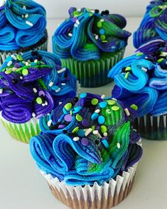 cupcakes with blue frosting and sprinkles sitting on a table