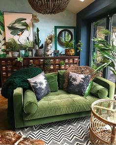 a living room filled with lots of green furniture and plants on top of the couch