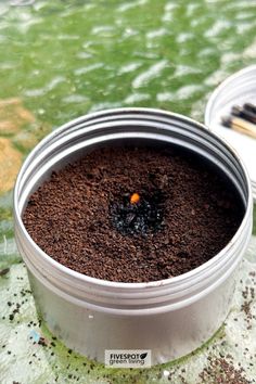 a metal container filled with dirt on top of a table