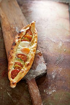 a piece of pizza sitting on top of a wooden cutting board next to a knife