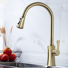 a golden faucet in a kitchen sink next to tomatoes