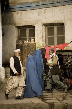 two men are walking down the street in front of a building with an open door