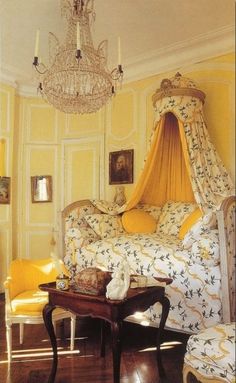 a canopy bed in a yellow bedroom with chandelier