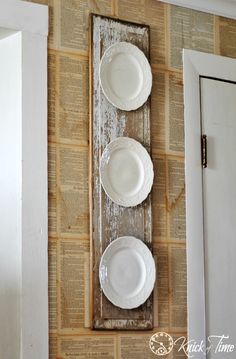 three white plates on a wooden board mounted to the wall