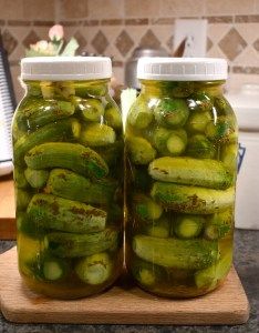 two jars filled with pickles sitting on top of a counter