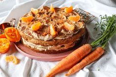 a cake with oranges on top and some carrots next to it sitting on a plate