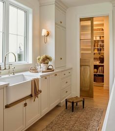 a kitchen with white cabinets and an area rug in front of the sink that is open