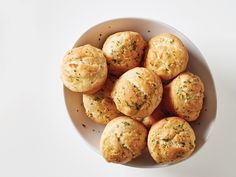 a white bowl filled with small muffins on top of a table