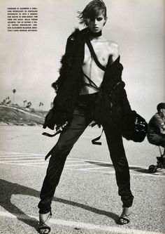 black and white photograph of a man with no shirt on standing in an empty parking lot