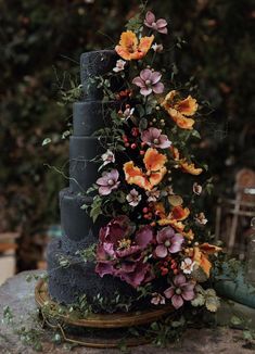 a three tiered cake with flowers on it's side and greenery around the edges