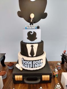 a three tiered cake is decorated with black and white frosting, featuring an image of a man in a suit