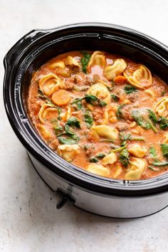 a crock pot filled with pasta and spinach