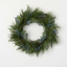 a green wreath with blue berries and pine needles on a white background, ready to be used as an ornament