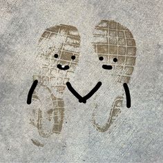 two faces are drawn on the ground with their hands in each other's pockets