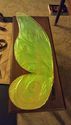 a green butterfly sitting on top of a wooden table next to scissors and wire cutters