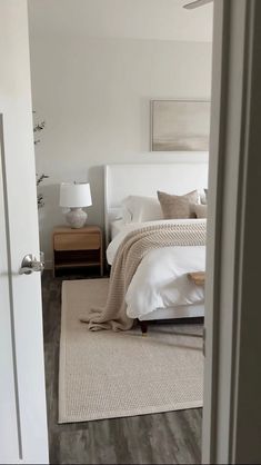 a bedroom with a bed, nightstand and lamp on the side of the door way