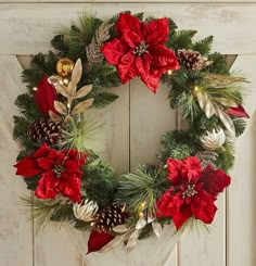 a christmas wreath hanging on a door with pine cones and red poinsettis