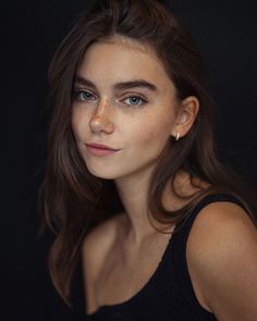 a beautiful young woman with blue eyes posing for a photo in front of a black background