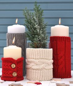 three knitted candles sitting next to each other on top of a white tablecloth