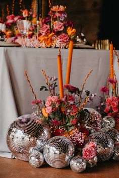 an arrangement of flowers and candles in front of a mirror ball centerpiece on a table