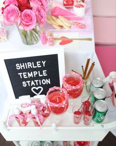 there is a table with pink flowers and candles on it that says shriley temple station