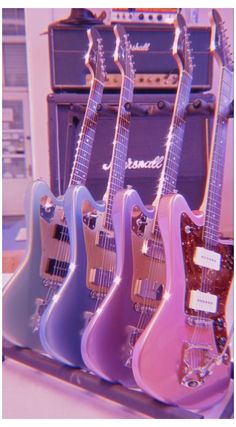 four electric guitars are lined up next to each other