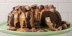 a chocolate cake with peanut butter frosting on a green plate next to a white brick wall