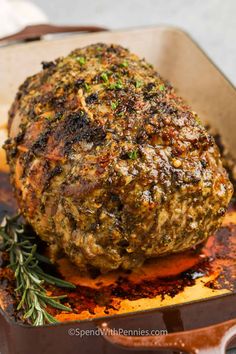 a close up of a meat in a pan with herbs on the side and seasoning