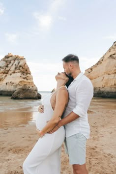 a pregnant couple embracing on the beach