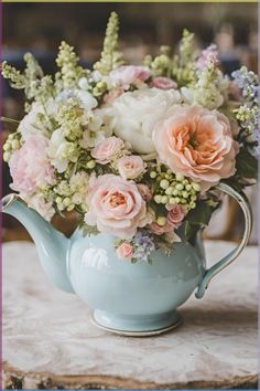 a blue tea pot filled with flowers on top of a table