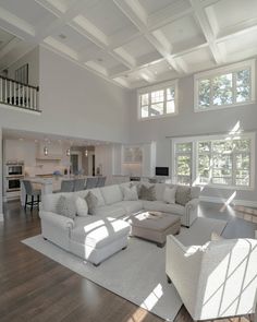 a large living room with white furniture and windows in the ceiling, along with hardwood flooring