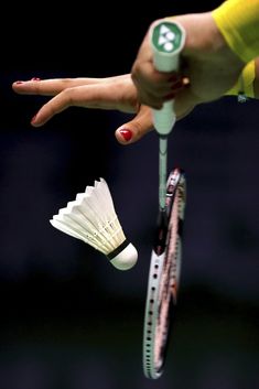 a woman's hand holding a tennis racket and several white fanned objects