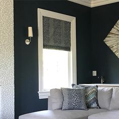 a living room filled with furniture and a window covered in shades of black, white and grey