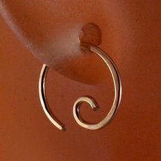 a pair of silver hoop earrings hanging from a hook on an orange wall with a white background