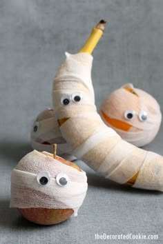 an apple with bandages wrapped around it and two bananas sitting next to each other on a gray surface